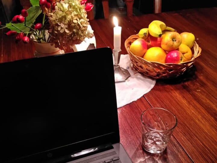 Ett bord redo för styrelsemöte. Dator, fruktkorg, levande ljus och vackra vinterblommor syns.